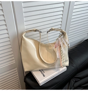 Detail of off-white hobo bag featuring lace charms and adjustable silver metal buckle
