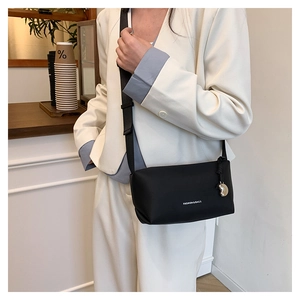Détail d'un sac bandoulière noir avec pendentif en cœur et texte mode blanc imprimé