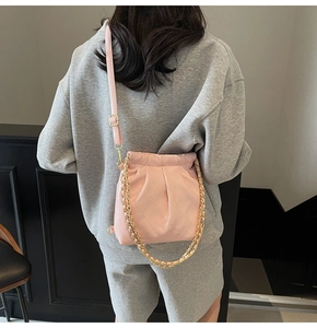 Pink quilted bucket bag with chain strap shown on a model for actual size perspective