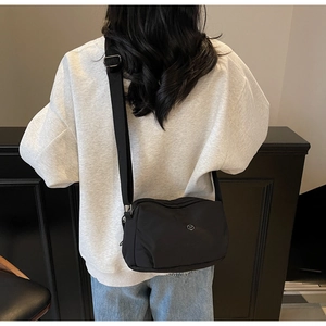 Vue arrière d'un sac bandoulière en nylon noir avec sangle réglable sur un mannequin