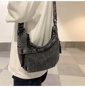Detail showing the acid wash texture and woven zipper pull of the large crossbody bag
