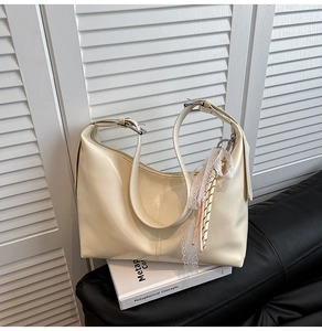 Close-up of cream hobo bag with white lace trim and silver buckle on wood shutters