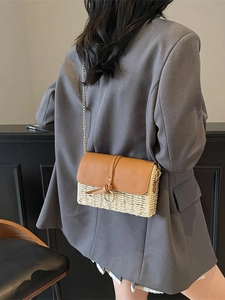 Fashionable straw crossbody bag with brown leather flap and gold chain strap on a model