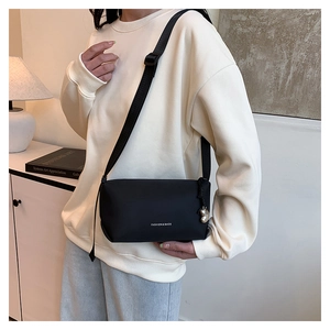 Détail d'un sac bandoulière noir en nylon avec sangle réglable et pendentif en métal argenté