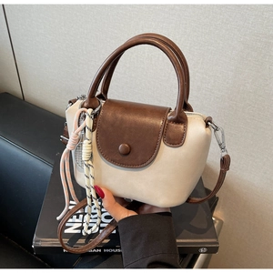 Detail of a mini two-tone beige and brown PU leather handbag with woven rope charm