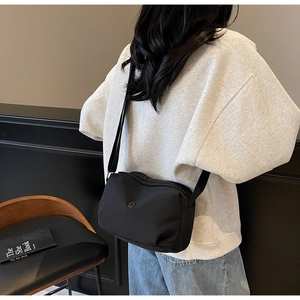 Detailed view of black nylon crossbody pillow bag with adjustable wide strap on model