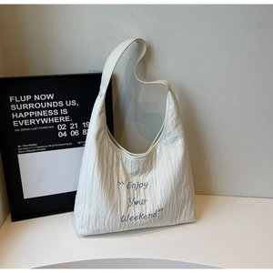 Detail of white pleated canvas tote bag with blue Enjoy Your Weekend embroidery