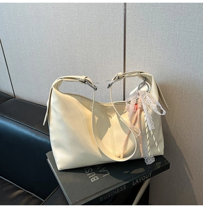 Detail of cream-white hobo bag showing smooth PU leather texture and lace accessory
