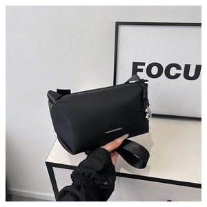 Détail du sac carré noir minimaliste avec lettrage blanc et pendentif en métal argenté