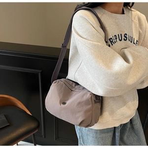 Detailed side view of a grey-purple nylon crossbody bag with wide adjustable shoulder strap