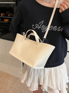 Minimalist off-white leather tote bag with dual handles and adjustable shoulder strap