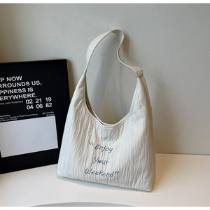 Detail of embroidered blue text on cream pleated canvas tote bag with wide strap