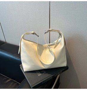 Detail of light yellow glossy hobo bag featuring silver buckles and smooth leather texture