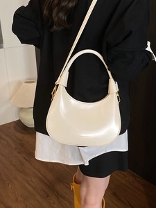 Elegante borsa a mezzaluna beige in pelle liscia, indossata come borsa a tracolla