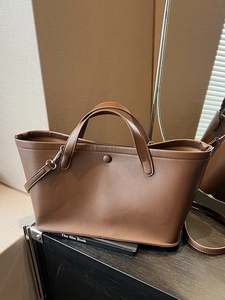 Deep brown minimalist tote bag with top handles and adjustable shoulder strap for women