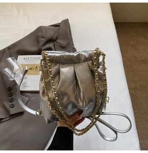 Close-up of silver quilted bucket bag featuring shiny metallic leather and gold chain