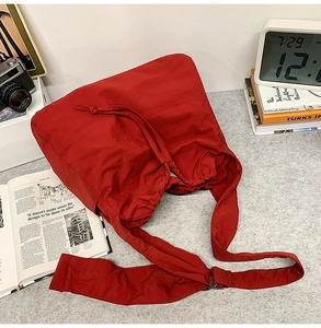 Détail du sac hobo en nylon rouge avec cordon et large bandoulière sur un bureau