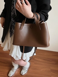 Minimalist dark brown matte leather bucket tote bag with top handle and shoulder strap
