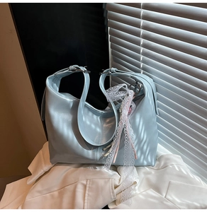 Detail of light blue glossy hobo bag with a delicate white lace ribbon accent