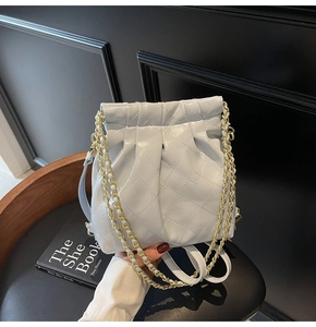 Détail du sac seau matelassé bleu clair avec bandoulière chaîne dorée et cordon