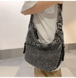 Detail of grey acid-wash denim crossbody bag with woven rope zipper and spacious interior