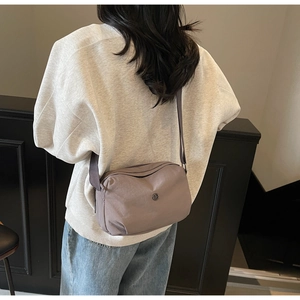 Gros plan d'un sac bandoulière gris-violet avec bandoulière réglable sur un mannequin