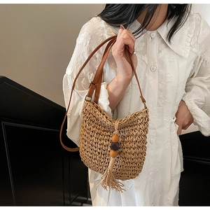 Dettaglio borsa a secchiello in paglia intrecciata vintage con nappa di perline di legno