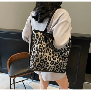 Detail of large leopard print tote bag with black canvas straps on model back