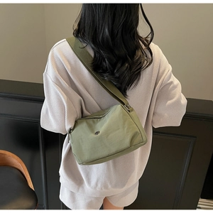 Vue détaillée d'un sac bandoulière vert olive en nylon avec une large sangle réglable