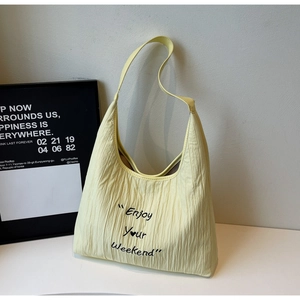 Detail showing the pleated texture and Enjoy Your Weekend print on a light yellow tote bag