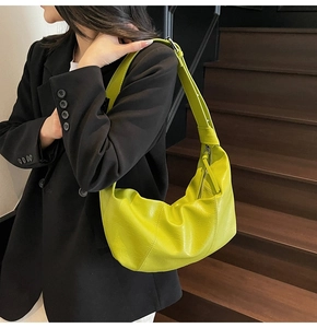 Lime green pleated crescent bag on model in a stylish modern minimalist setting