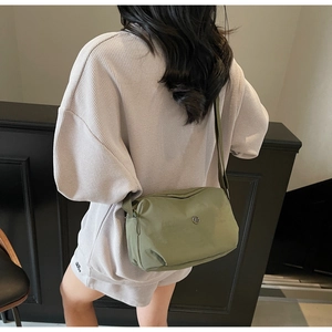 Détail du sac bandoulière en nylon vert olive avec logo métallique et bandoulière réglable