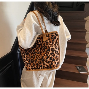 Close-up of a large leopard print tote bag worn on shoulder in a stylish indoor setting