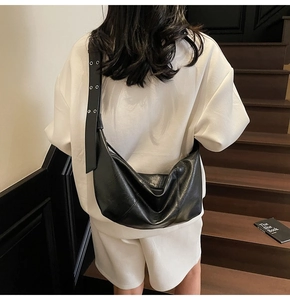 Detail of black wax leather crossbody bag featuring adjustable silver eyelet strap