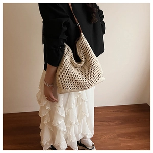 Chic cream hollow-out woven crochet shoulder bag with a brown leather strap shown on model