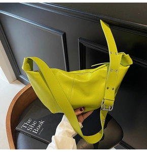 Macro detail of neon green crescent bag with metal eyelet adjustable shoulder strap