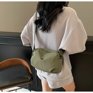 Sac bandoulière en nylon vert armée avec logo en métal circulaire sur un modèle en scène