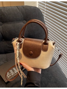 Chic two-tone mini crossbody bag with top handles and decorative charm in beige and brown