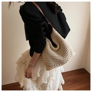 Detail of crochet beige beach bag with hollow texture and brown leather strap