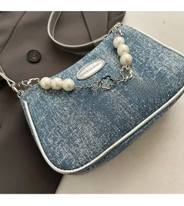 Detail of blue denim shoulder bag with sparkling sequins and decorative pearl chain