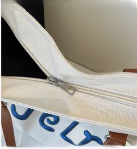Close-up of smooth silver metal zipper on white canvas tote bag with embroidery