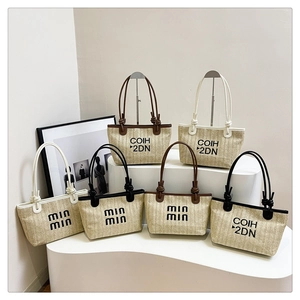 Detail of straw woven tote bags with knotted shoulder straps and text print design