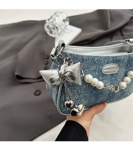 Detail of light blue denim underarm bag with silver rivets and pearl chain handle