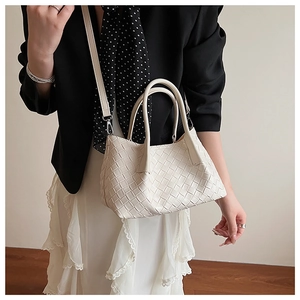 Détail de la texture tressée du sac seau crème avec poignées et bandoulière amovible