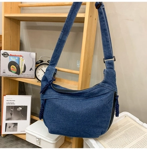 Detailed view of the denim hobo bag featuring a knotted zipper pull and adjustable strap