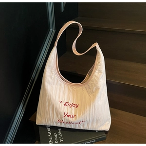 Detail of light pink wrinkled fabric tote bag with Enjoy Your Weekend red embroidery
