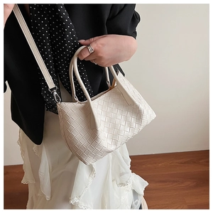 Détail du sac à main tressé crème montrant la texture du cuir et la bandoulière amovible