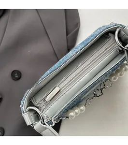 Macro view showing smooth metal zipper and silver flower pearl charm on denim bag