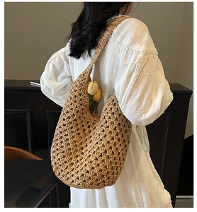 Detail shot of the hollow woven straw shoulder bag with natural mesh texture on a model
