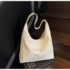 Detail of cream crinkled canvas tote bag with Enjoy Your Weekend embroidery on a book